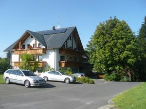 due auto parcheggiate in un parcheggio di fronte a una casa di Hotel Bergblick a Warmensteinach