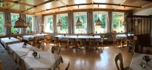 una sala da pranzo con tavoli, sedie e finestre di Hotel Bergblick a Warmensteinach