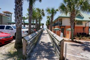 einen hölzernen Gehweg mit Palmen und einem Gebäude in der Unterkunft Beachside Inn in Destin