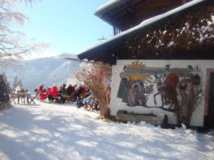 eine Gruppe von Menschen, die vor einem Gebäude im Schnee sitzen in der Unterkunft Berghotel Blaickner's Sonnalm in Zell am See