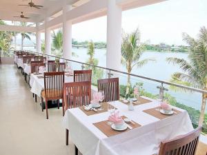 un restaurante con mesas y sillas con vistas al agua en Century Riverside Hotel Hue, en Hue