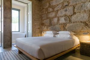 una camera da letto con un muro in pietra e un letto con cuscini di Armazém Luxury Housing- Architectural & Design Hotel a Porto