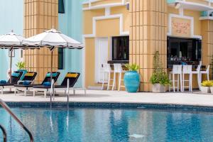 een zwembad met stoelen en parasols naast een gebouw bij Wave Hotel Pattaya in Pattaya