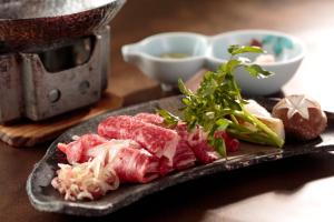 um prato de alimentos com carne e legumes sobre uma mesa em Kinseikan Seseragi em Minakami