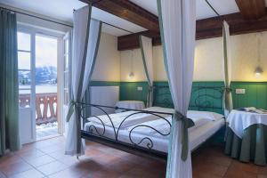 a bedroom with a canopy bed and a balcony at Quinz - Locanda Al Lago in Misurina