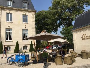 a group of people sitting at a table under an umbrella at Les Suites du Champagne de Venoge in Épernay