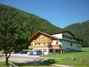 un grande edificio con auto parcheggiate in un parcheggio di Pension Wiesenhof a Campo di Trens