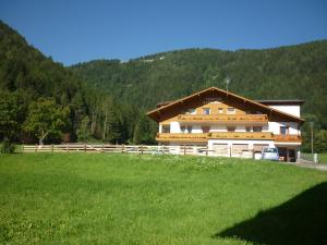 un edificio con un campo verde davanti di Pension Wiesenhof a Campo di Trens