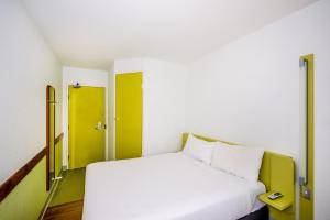 - une chambre avec un lit blanc et une porte jaune dans l'établissement ibis Budget - Newcastle, à Newcastle