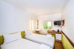 Cette chambre comprend deux lits et une télévision. dans l'établissement ibis Budget - Newcastle, à Newcastle