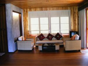 a living room with a couch and two windows at Baan Nana Villa in Mae Nam