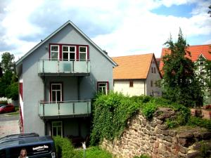 Casa blanca con ventanas rojas y pared de piedra. en Apartments am Storchenturm im Hellgrevenhof, en Eisenach