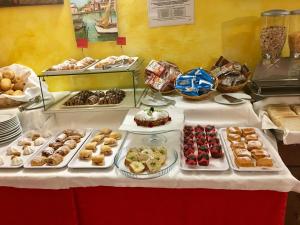 una mesa con diferentes tipos de pasteles. en Hotel Fortuna, en Caorle