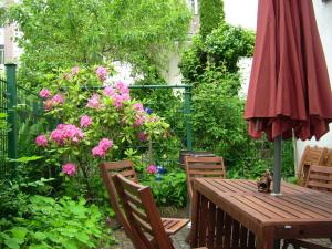 ein Holztisch und Stühle mit einem Sonnenschirm und Blumen in der Unterkunft Ferienwohnungen "Altes Bachhaus" in Eisenach