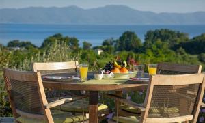 uma mesa de madeira com uma taça de fruta e copos de sumo de laranja em Iakovakis Suites & Spa em Koropi