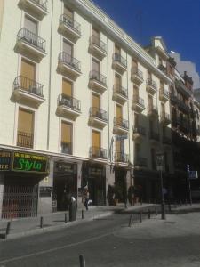 Un grand bâtiment blanc avec balcon se trouve dans une rue. dans l'établissement Hostal Triana, à Madrid