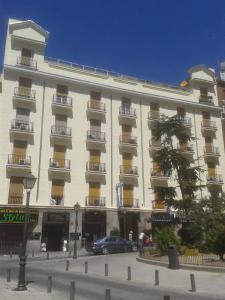 un grand bâtiment blanc avec des voitures garées devant lui dans l'établissement Hostal Triana, à Madrid