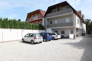 due auto parcheggiate in un parcheggio di fronte a un edificio di Hévízi Tópark Panzió a Hévíz