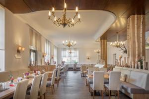 uma sala de jantar com mesas e cadeiras e um lustre em Hotel Vier Jahreszeiten em Garmisch-Partenkirchen