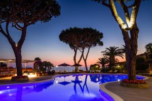 uma piscina à noite com árvores e luzes em Cala del Porto Punta Ala em Punta Ala