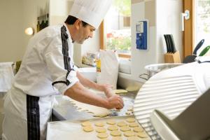 een chef-kok bereidt eten in een keuken bij Hotel Garni Lastei in Pozza di Fassa