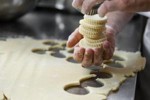 een persoon die koekjes maakt bovenop een taart bij Hotel Garni Lastei in Pozza di Fassa