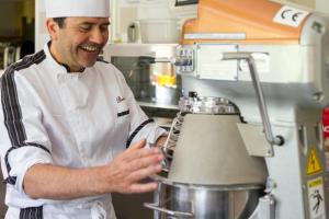 een kok in een keuken met een blender bij Hotel Garni Lastei in Pozza di Fassa