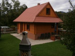 une cabane en rondins avec un toit rouge, une table et des chaises dans l'établissement Drevenica Silvia, à Liptovský Mikuláš