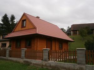 une maison en bois avec un toit rouge et une clôture dans l'établissement Drevenica Silvia, à Liptovský Mikuláš