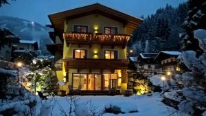 een huis met een balkon in de sneeuw 's nachts bij Landhaus Marlies in Zell am See