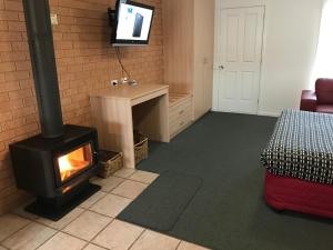 ein Wohnzimmer mit einem Kamin und einem TV in der Unterkunft Beachcomber Motel & Apartments in Apollo Bay