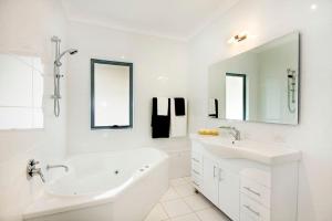 Baño blanco con bañera y lavamanos en The Beach Townhouse, en Hawks Nest