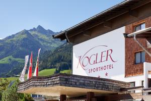 un panneau sur un bâtiment avec des montagnes en arrière-plan dans l'établissement Sporthotel Kogler, à Mittersill