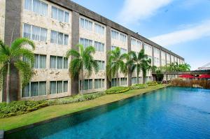 un bâtiment avec une piscine en face d'un bâtiment dans l'établissement Aston Denpasar Hotel & Convention, à Denpasar