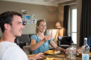 Eine Frau, die mit einem Glas Wein am Tisch sitzt. in der Unterkunft Beach Apartments Heiligenhafen in Heiligenhafen