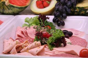 a plate of food with meat and vegetables and fruit at Kurhotel Fürstenhof by David in Blankenburg