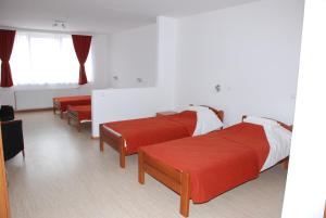 1 dormitorio con 2 camas con colchas rojas y ventana en M Garni Hotel, en Vranje