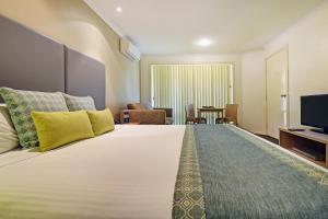 a hotel room with a large bed and a television at BreakFree Aanuka Beach Resort in Coffs Harbour