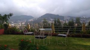 een tafel en stoelen in de tuin met uitzicht bij Wyoming Heritage in Ooty