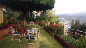 een tafel en stoelen in een tuin met bloemen bij Wyoming Heritage in Ooty