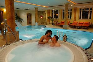 a man and a woman sitting in a hot tub at Hotel Brunnenhof in Bayerisch Eisenstein