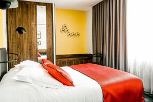 a bedroom with a bed with red pillows on it at Hostellerie Du Chapeau Rouge in Dijon