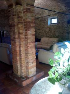 una sala de estar con un pilar de piedra y un sofá en Case Cordovani, en Magliano in Toscana