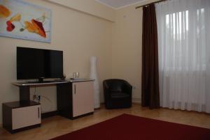 a living room with a flat screen tv and a chair at Villa Parc in Cluj-Napoca