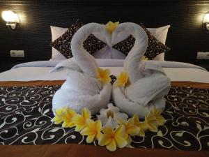 two swans sitting on a bed with flowers on it at Asta House in Kuta