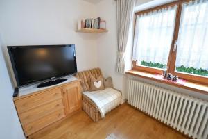 a living room with a flat screen tv and a chair at Apartments Dolomie in Ortisei