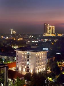 un bâtiment éclairé devant une ville la nuit dans l'établissement Amaris Hotel Darmo Surabaya, à Surabaya