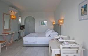 Ammos Naxos Exclusive Apartments & Studios في ناكسوس تشورا: غرفة نوم بسرير ابيض ومكتب