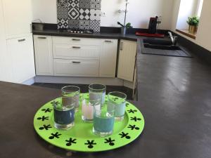 a green plate with four glasses on a table at chambre d'hôte-abc in Reims