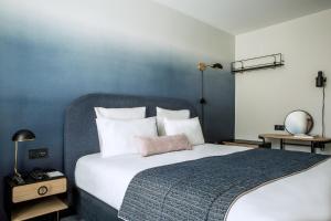 um quarto com uma cama grande e uma parede azul em L'Imprimerie Hôtel em Clichy